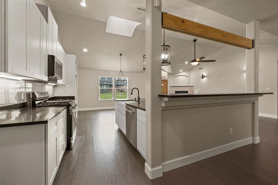 Kitchen with stainless steel appliances, a ceiling fan, dark countertops, white cabinets, and recessed lighting