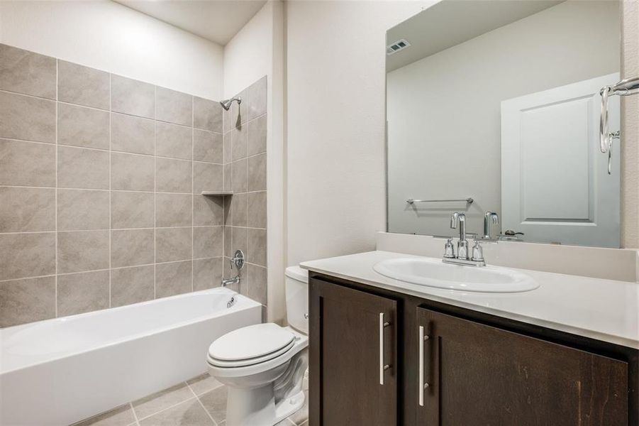 Full bathroom featuring tile patterned flooring, toilet, vanity, and tiled shower / bath