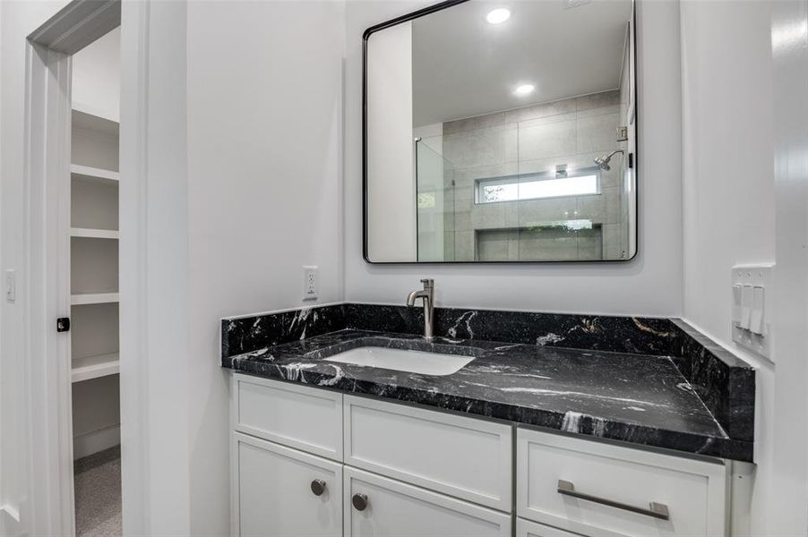 Bathroom with a stall shower, vanity, a walk in closet, and recessed lighting