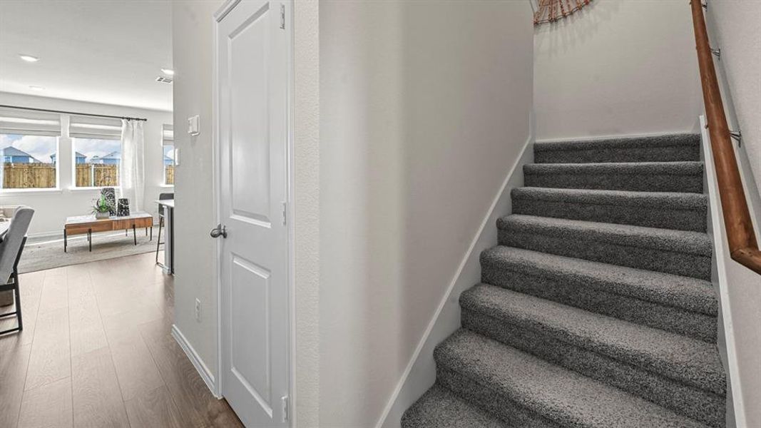 Staircase with wood finished floors and recessed lighting