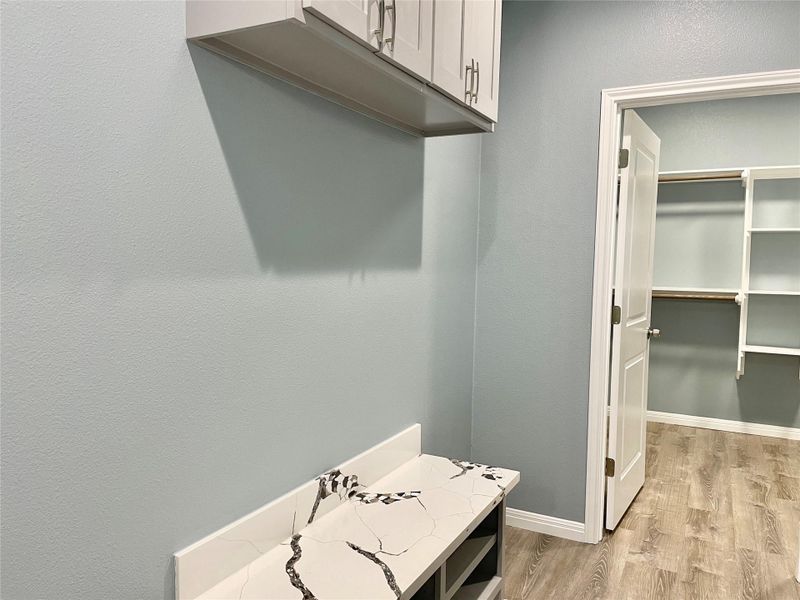 Functional laundry room offers a built-in counter for folding and storage, with an adjacent walk-in closet.