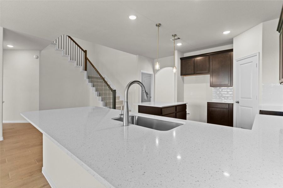 Close up view from the kitchen island showcasing the stunning granite countertops and spacious breakfast bar seating area. The large island provides plenty of workspace for cooking and entertaining while the kitchen remains open to the family room and dining area.