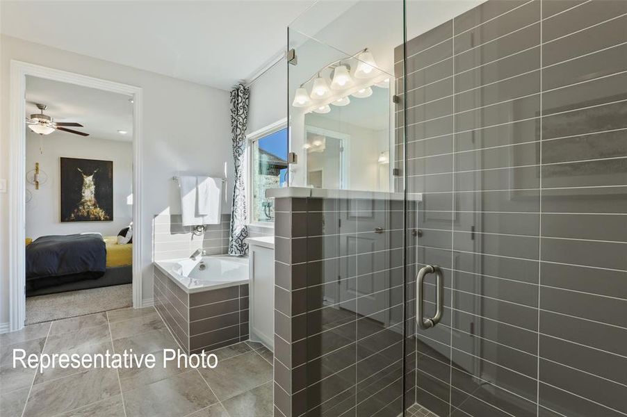Bathroom featuring a glass-enclosed shower with horizontal gray tile, a built-in soaking tub with matching gray tile surround, and a vanity with a mirror and multi-bulb light fixture