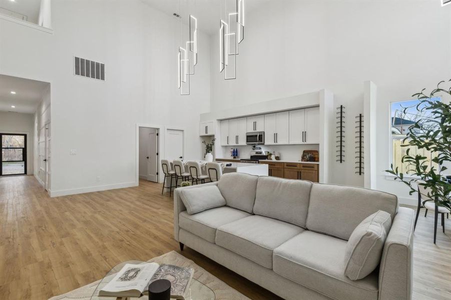 Living room featuring a towering ceiling and light hardwood / wood-style floors