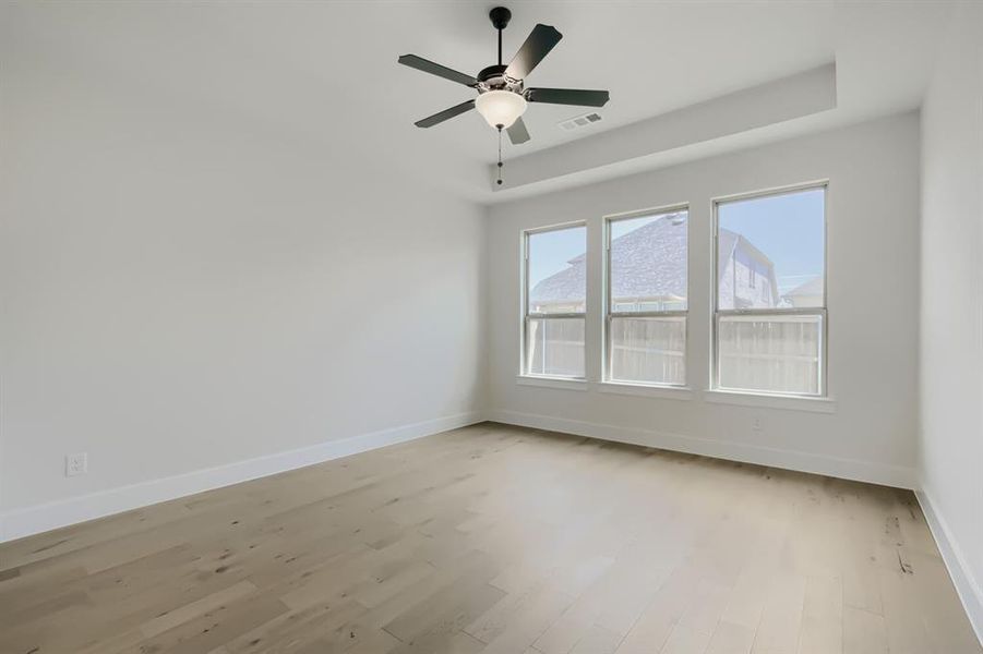 Bright interior space featuring wood-finish flooring, white baseboards, and a contemporary ceiling fan with integrated lighting
