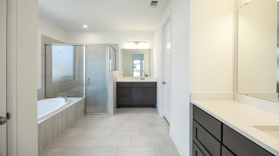 Bathroom with a bath, two vanities, a shower stall, light tile patterned floors, and recessed lighting