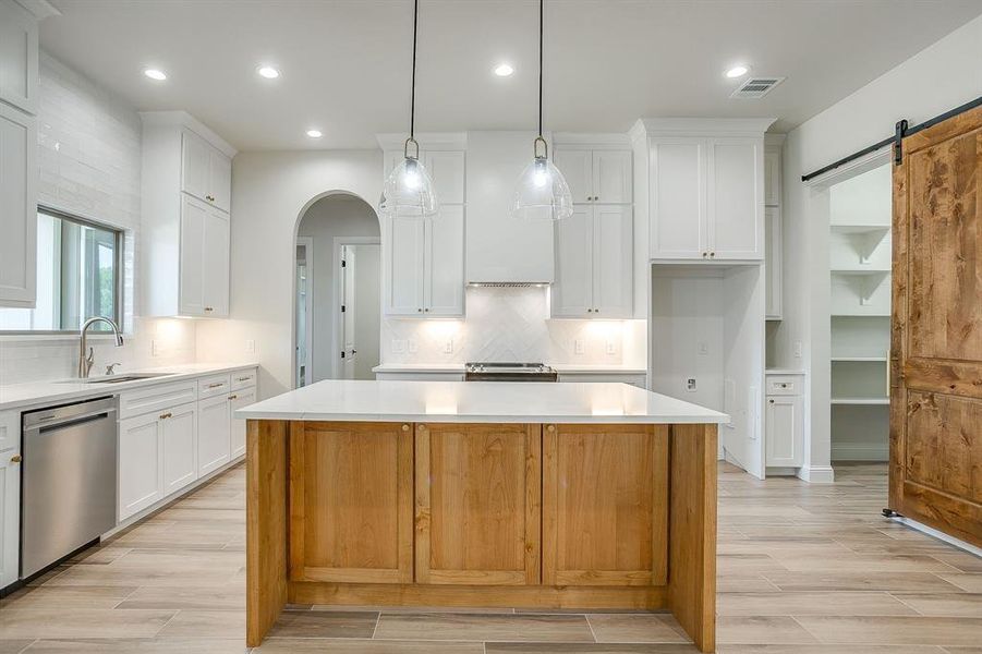 Kitchen with a barn door, wood tiled floors, a kitchen island, dishwasher, and recessed lighting Kitchen with a barn door, wood tiled floors, a kitchen island, dishwasher, and recessed lighting