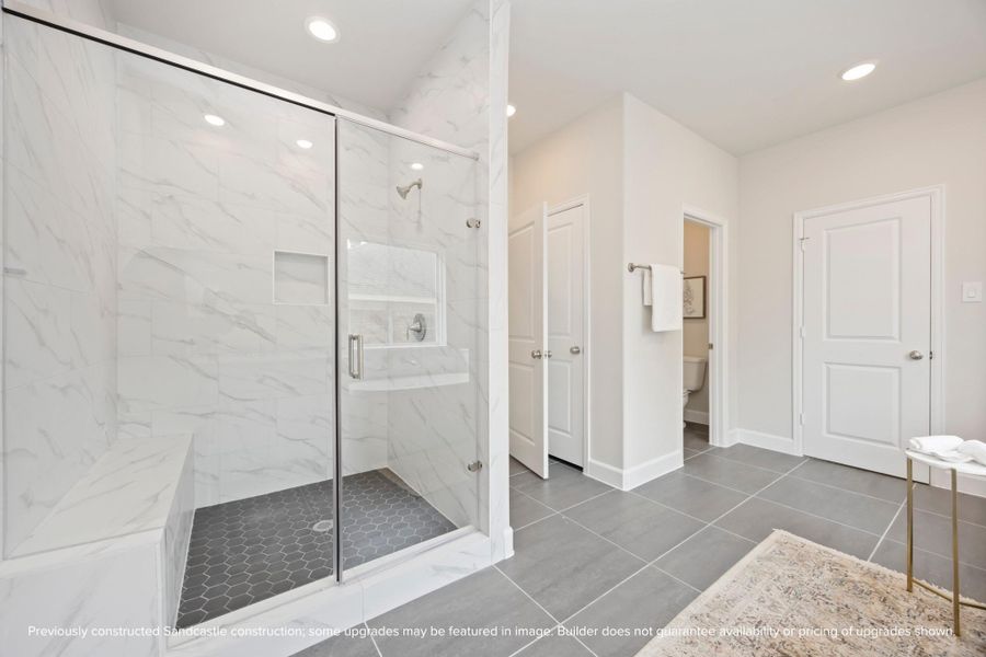 A large, step-in shower with bench seating and a separate water closet redefine luxury, making every morning a spa-like experience. A large, step-in shower with bench seating and a separate water closet redefine luxury, making every morning a spa-like experience.