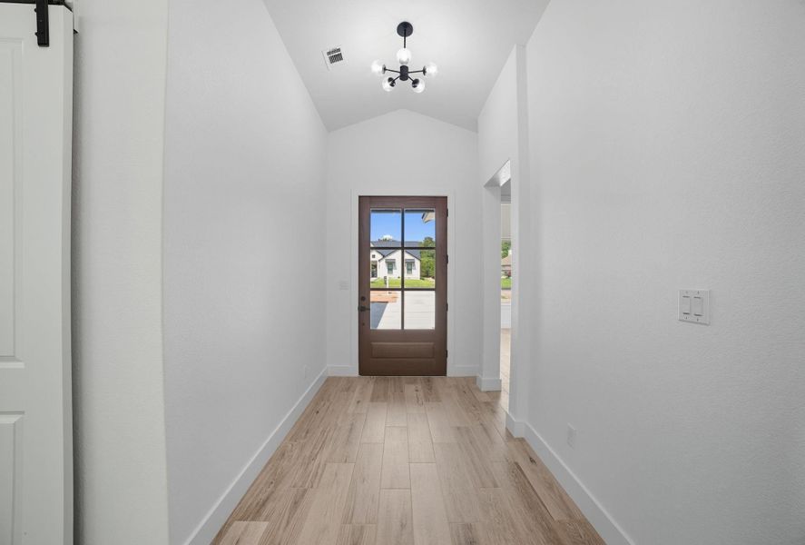 Entryway with wood finished floors, a chandelier, and vaulted ceiling Entryway with wood finished floors, a chandelier, and vaulted ceiling