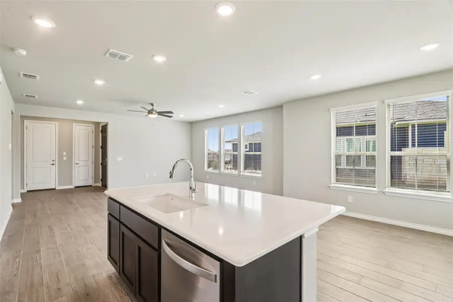 Kitchen with stainless steel dishwasher, light wood-style floors, light countertops, ceiling fan, and recessed lighting