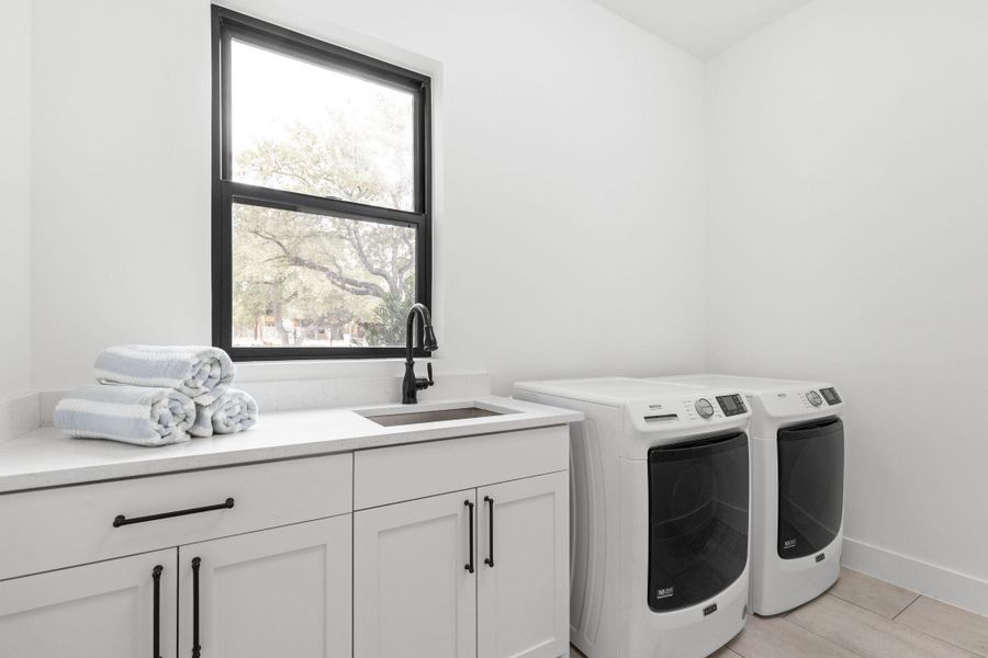 Washroom featuring washing machine and clothes dryer, cabinet space, and light tile patterned floors