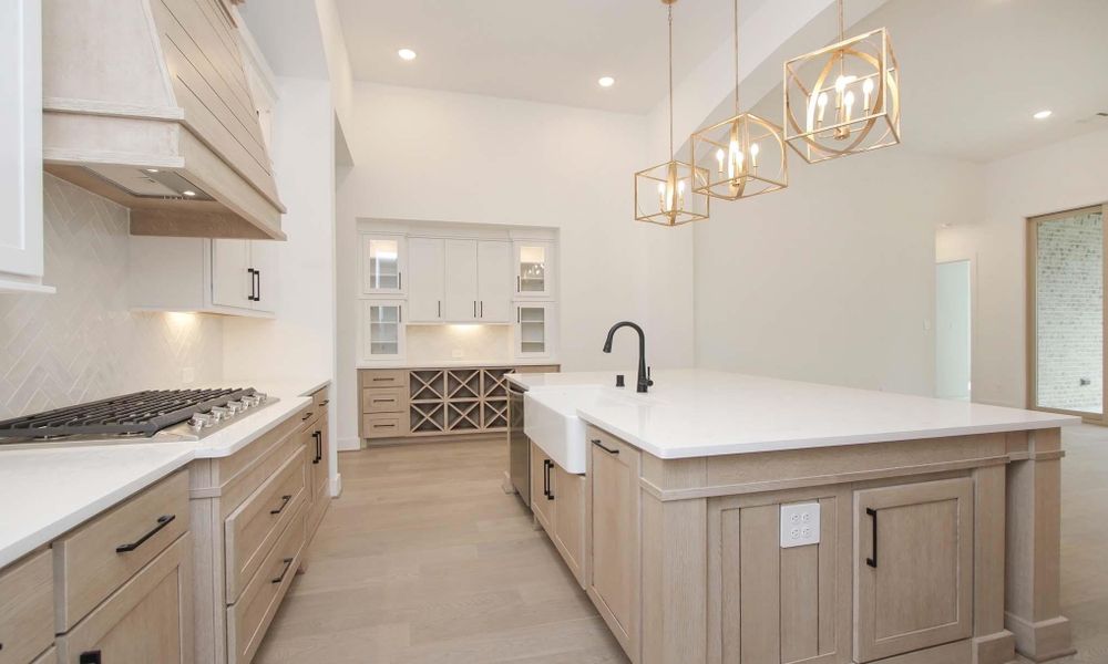Kitchen with a chandelier, tasteful backsplash, custom range hood, light countertops, and recessed lighting