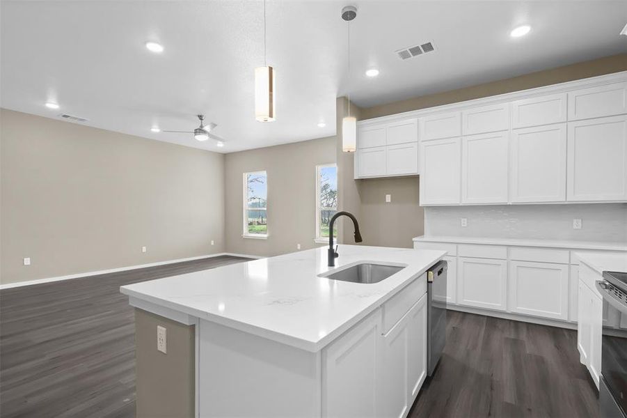 Kitchen featuring decorative light fixtures, an island with sink, sink, white cabinets, and stainless steel appliances