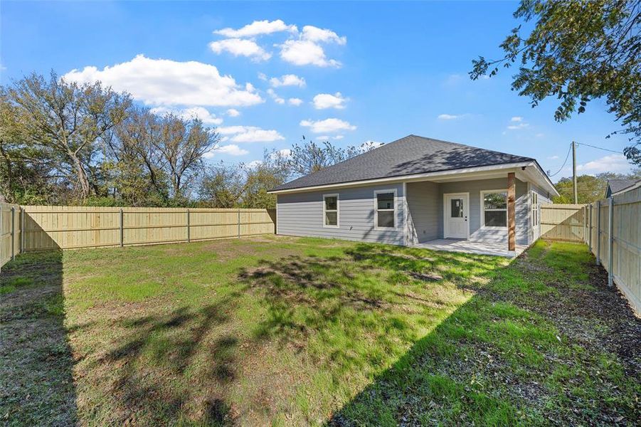 Back of house with a patio area, roof with shingles, and a fenced backyard