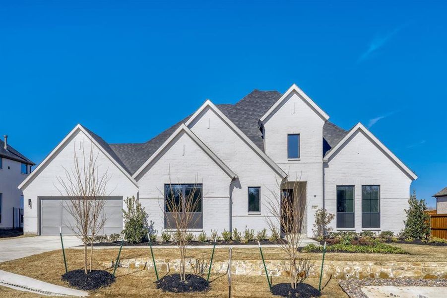 View of front of property featuring driveway, brick siding, and an attached garage