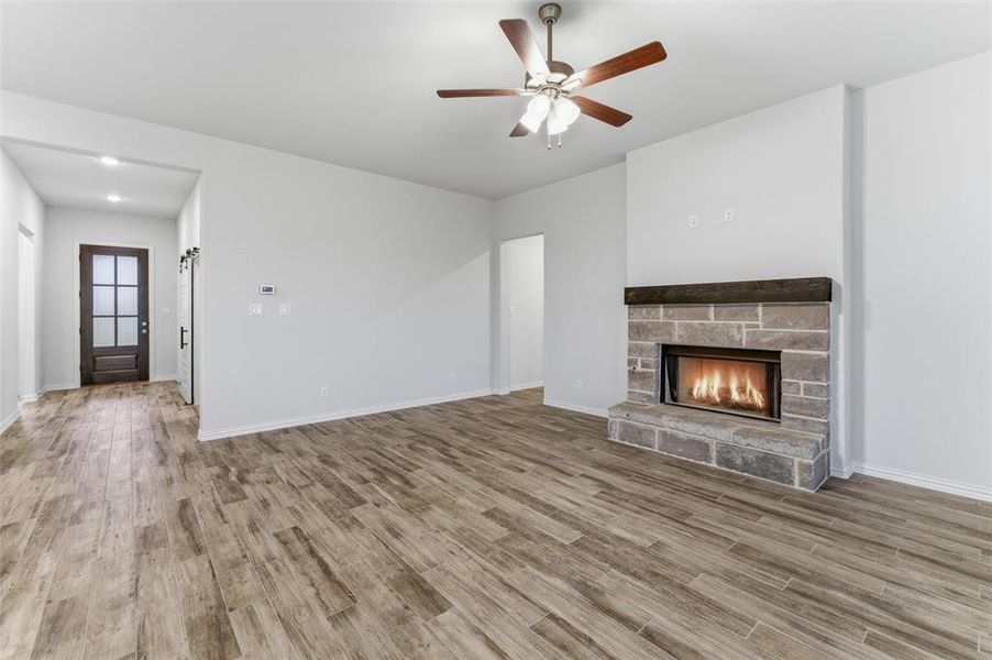 Living area featuring wood-finish flooring and a stone-clad fireplace with a dark wood mantel