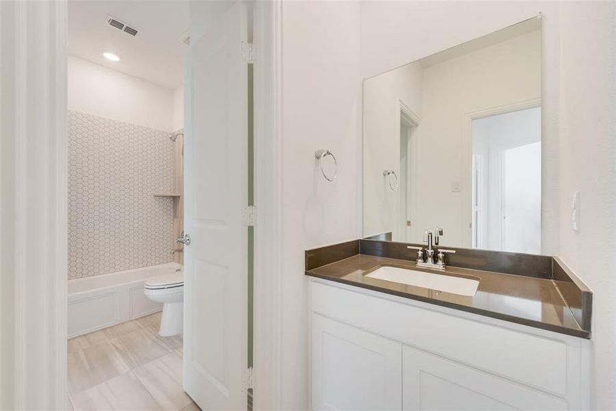 Full bathroom with toilet, vanity, and tiled shower / bath