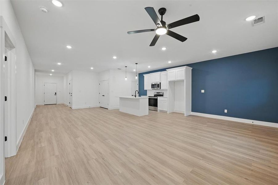 Unfurnished living room featuring a sink, ceiling fan, light wood-style floors, recessed lighting, and baseboards