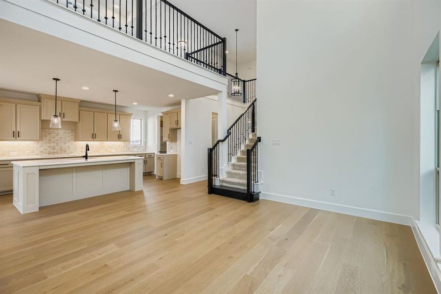 Unfurnished living room featuring stairway, light wood-style flooring, recessed lighting, and a towering ceiling Unfurnished living room featuring stairway, light wood-style flooring, recessed lighting, and a towering ceiling
