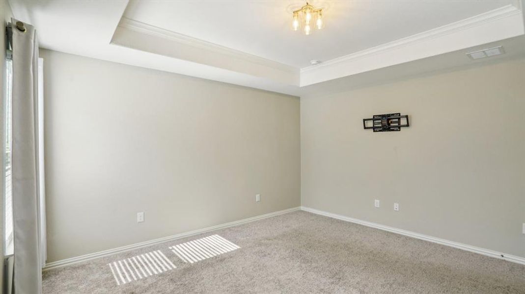 Carpeted spare room featuring crown molding and a raised ceiling Carpeted spare room featuring crown molding and a raised ceiling