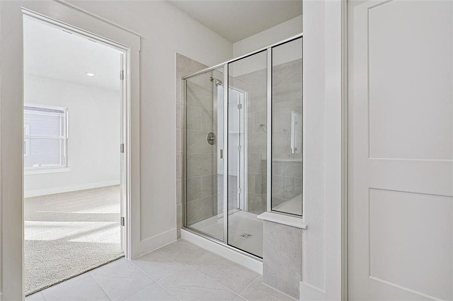 Full bath with a shower stall and tile patterned floors