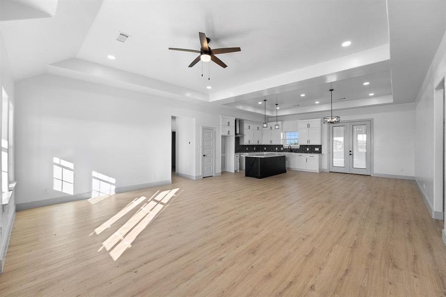 Unfurnished living room featuring recessed lighting, light wood finished floors, ceiling fan, and a chandelier