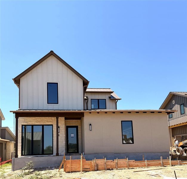 A new construction home with contemporary architecture features a mix of stucco, stone, and board and batten siding.