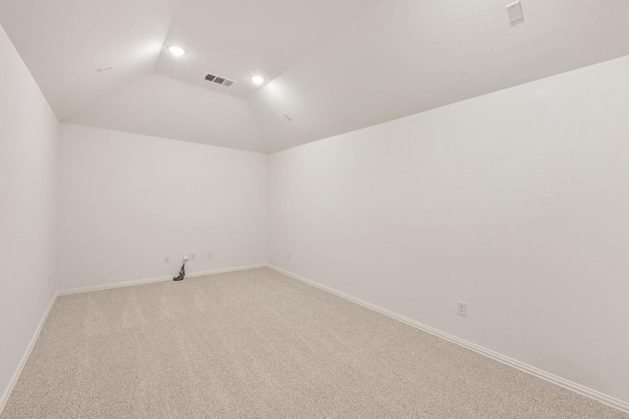 Empty room with vaulted ceiling, recessed lighting, and beige carpet flooring Empty room with vaulted ceiling, recessed lighting, and beige carpet flooring