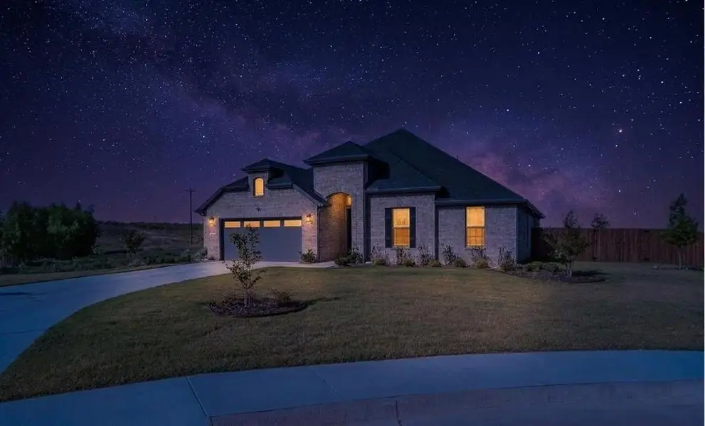 Brick exterior residence with a dark shingle roof, arched entry with a modern door, and a 2.5-car garage