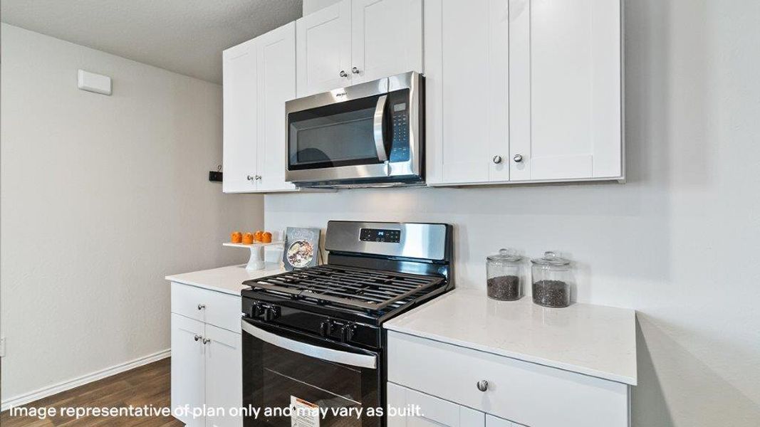 A streamlined kitchen presents sleek white cabinetry, a built-in microwave, and a modern gas range. A streamlined kitchen presents sleek white cabinetry, a built-in microwave, and a modern gas range.