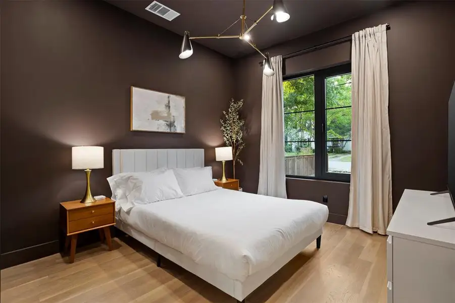 Spacious room featuring light wood-finish flooring, dark accent walls, and a large window with black framing