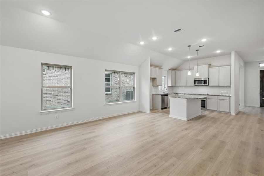 Kitchen with a kitchen island, open floor plan, hanging light fixtures, stainless steel appliances, and lofted ceiling