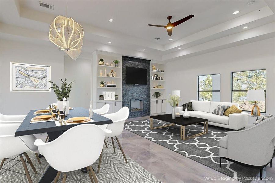 Living room with a fireplace, a raised ceiling, built in features, and ceiling fan