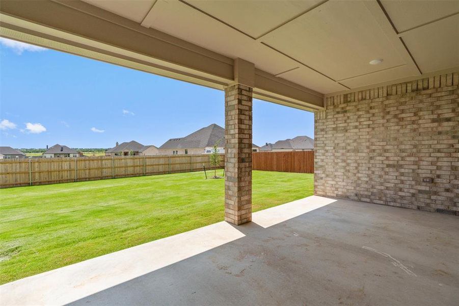 Covered patio with a concrete slab, brick support columns, and an exposed brick exterior wall Covered patio with a concrete slab, brick support columns, and an exposed brick exterior wall
