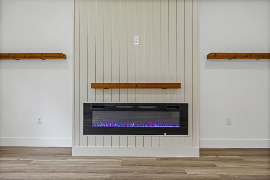 Integrated electric fireplace with a wood-finish mantel, surrounded by shiplap-style accent wall Integrated electric fireplace with a wood-finish mantel, surrounded by shiplap-style accent wall