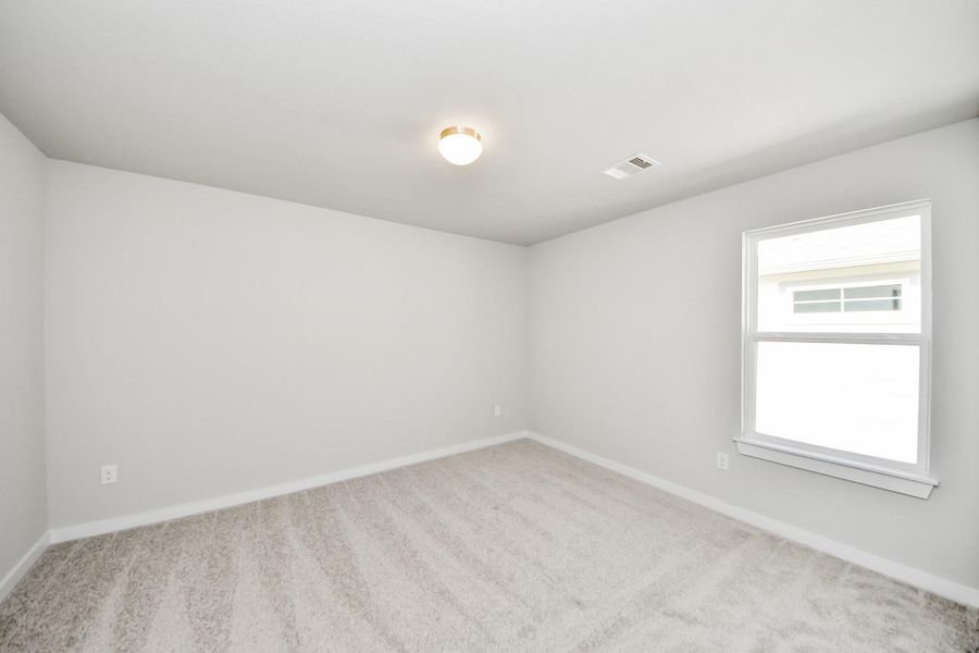 Secondary bedroom features plush carpeting, large windows that let in plenty of natural light, bright paint, and spacious closets. Sample photo of completed home with similar floor plan. Actual colors and selections may vary.