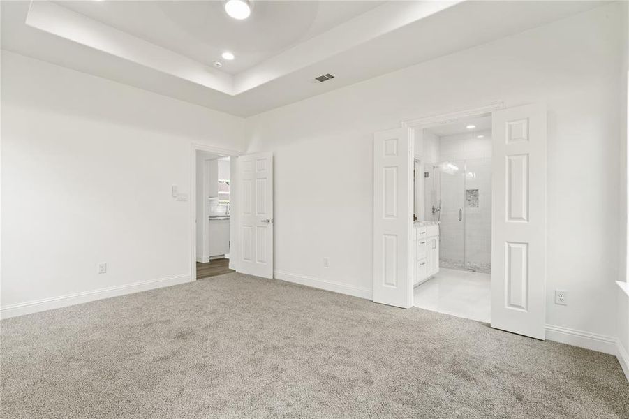 Spacious interior featuring light gray carpeting and a tray ceiling with recessed lighting