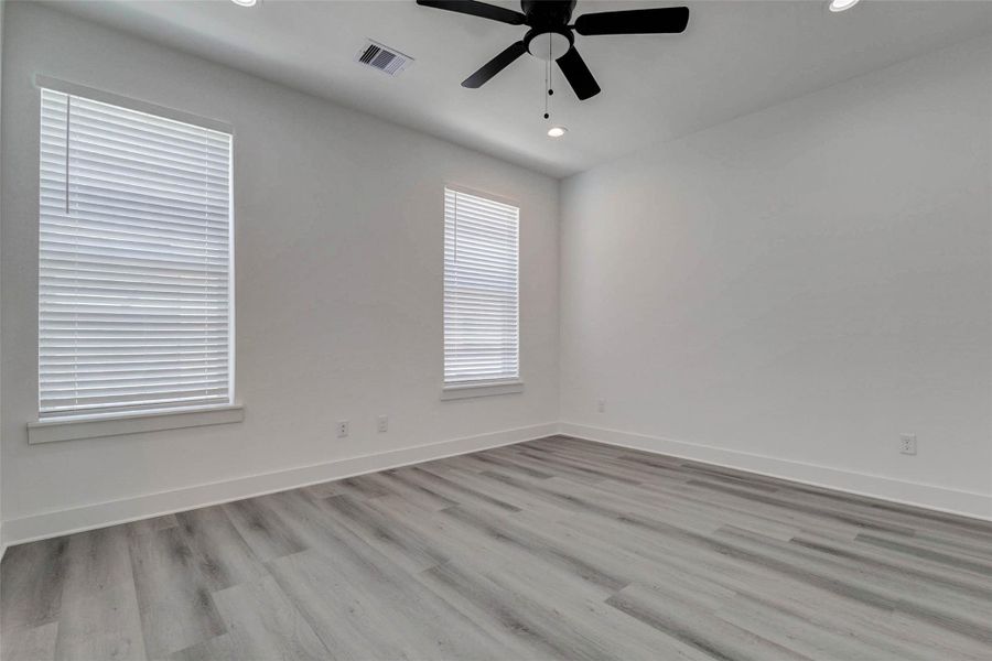 This light-filled bedroom offers two tall windows, neutral finishes, gray-toned plank flooring, recessed lighting, and a modern ceiling fan. Generous wall space provides flexibility for furniture placement, creating a comfortable retreat that can easily accommodate a bedroom, home office, or creative space. This light-filled bedroom offers two tall windows, neutral finishes, gray-toned plank flooring, recessed lighting, and a modern ceiling fan. Generous wall space provides flexibility for furniture placement, creating a comfortable retreat that can easily accommodate a bedroom, home office, or creative space.