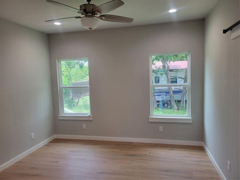 Room featuring wood-finish flooring, two large windows, white trim, a ceiling fan, and recessed lighting