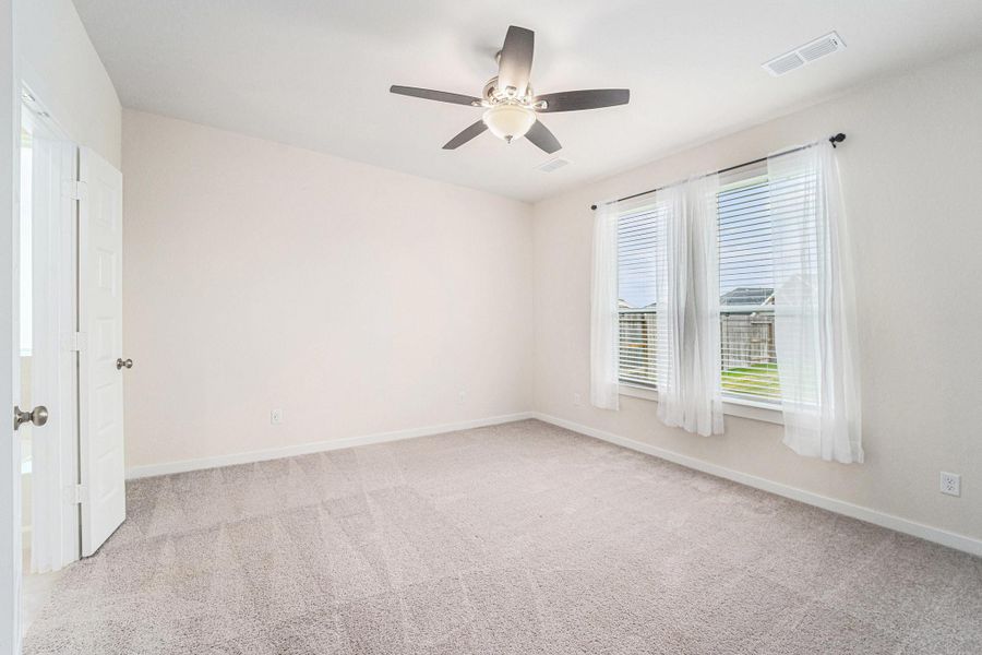 The large primary bedroom is located at the back of the house, has plush carpet, ceiling fan and double doors leading into the en-suite The large primary bedroom is located at the back of the house, has plush carpet, ceiling fan and double doors leading into the en-suite