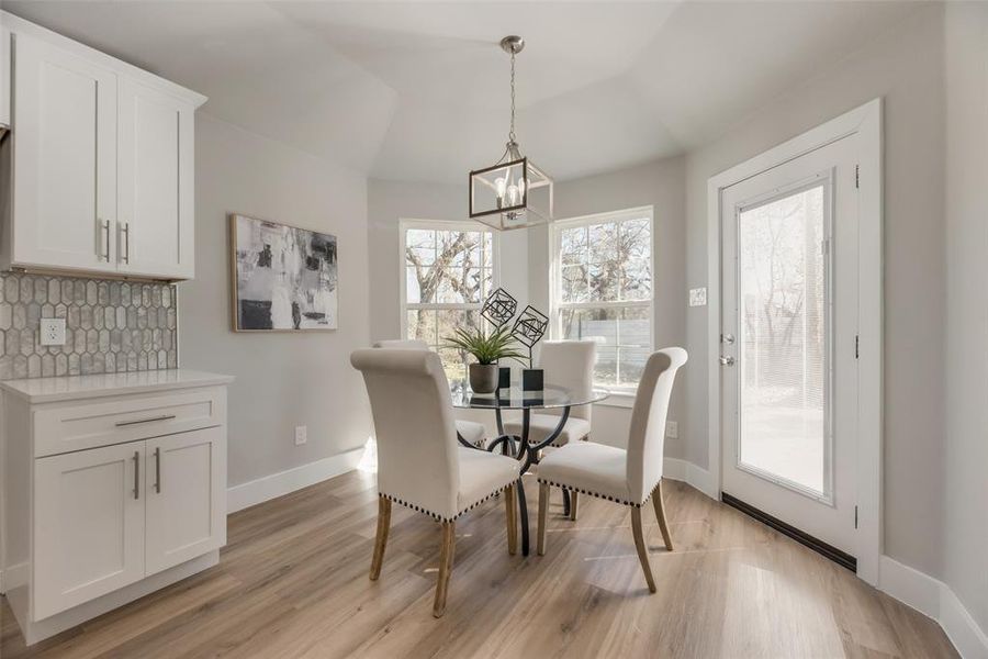 Dining space with an inviting chandelier, light wood-type flooring, and lofted ceiling