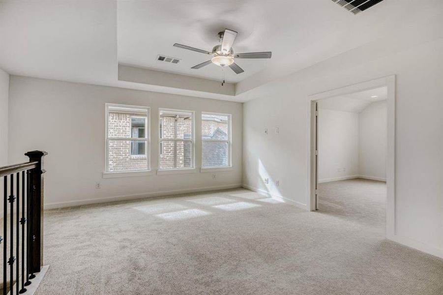 Spare room with carpet flooring, a ceiling fan, and a raised ceiling