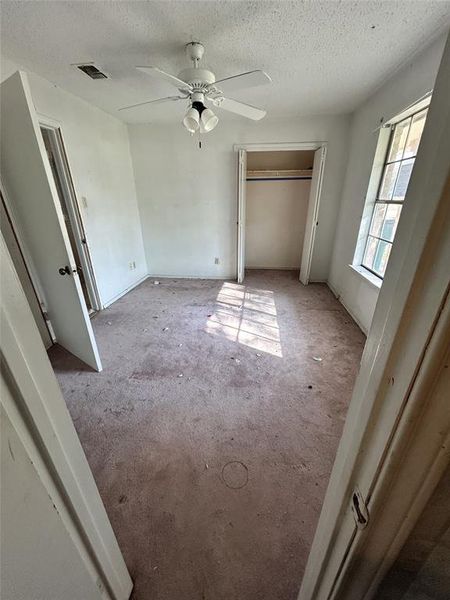 Unfurnished bedroom featuring carpet floors, a closet, a textured ceiling, and ceiling fan Unfurnished bedroom featuring carpet floors, a closet, a textured ceiling, and ceiling fan