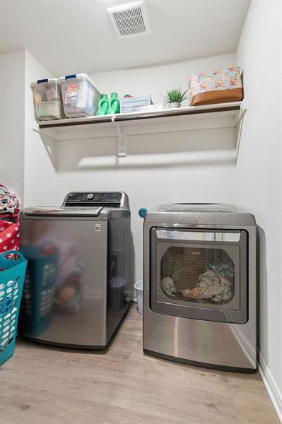 The laundry area features a washer and dryer, light-colored flooring, and an overhead shelf for storage