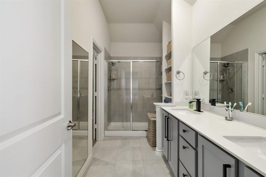 Bathroom featuring a stall shower, double vanity, and light tile patterned floors Bathroom featuring a stall shower, double vanity, and light tile patterned floors