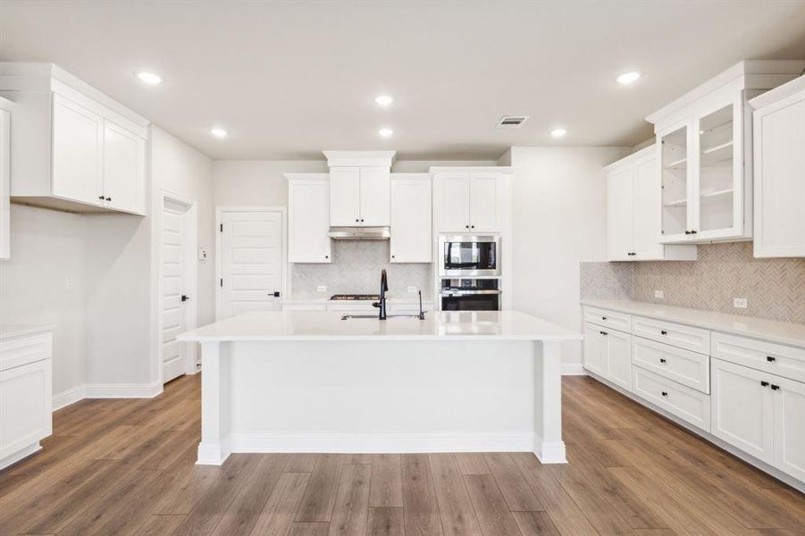 Kitchen featuring appliances with stainless steel finishes, a kitchen island with sink, dark hardwood / wood-style floors, and white cabinets