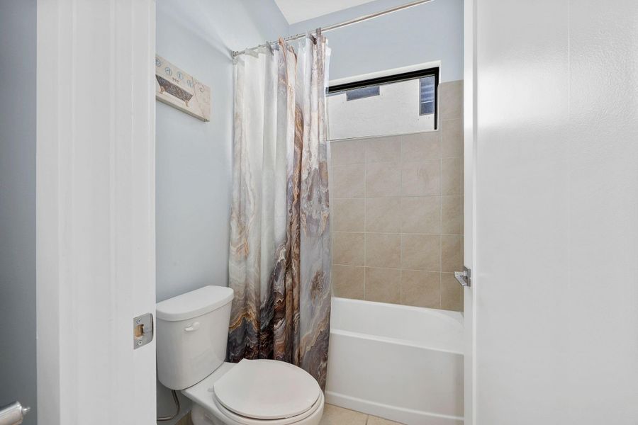 Full bathroom featuring toilet and shower / tub combo with curtain