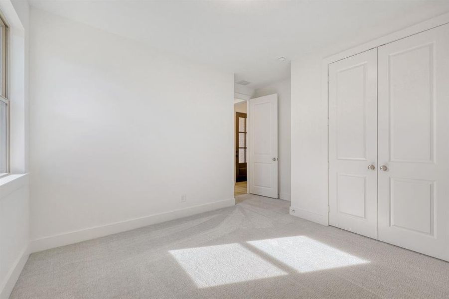 Unfurnished bedroom with light carpet and a closet