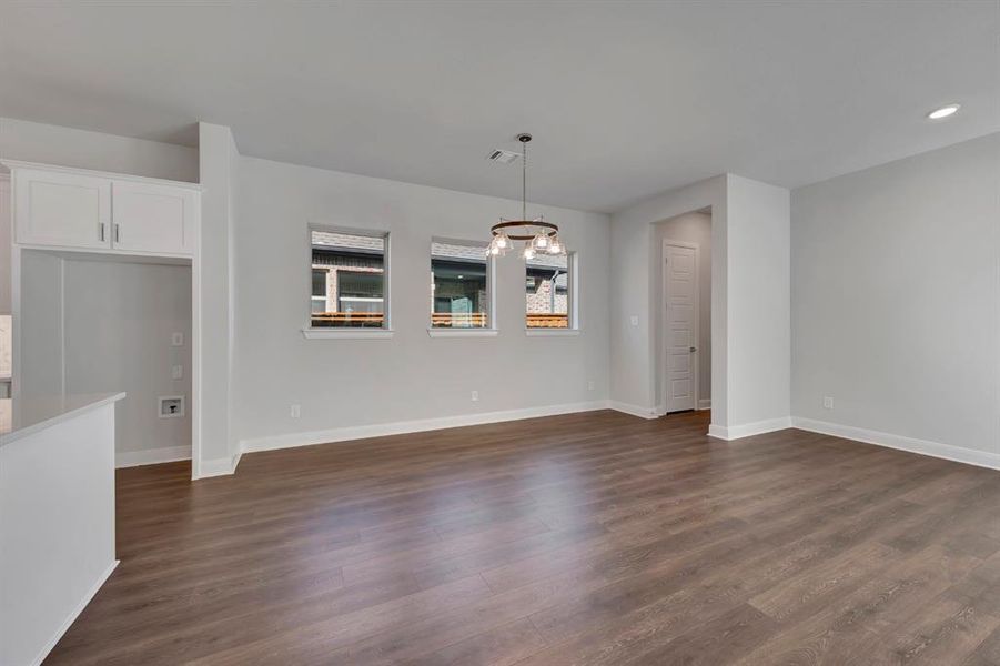 Unfurnished dining area featuring dark wood-style flooring and a chandelier