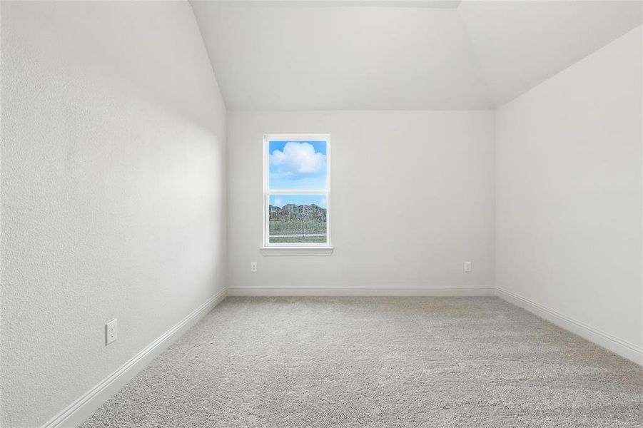 Empty room with light carpet and lofted ceiling